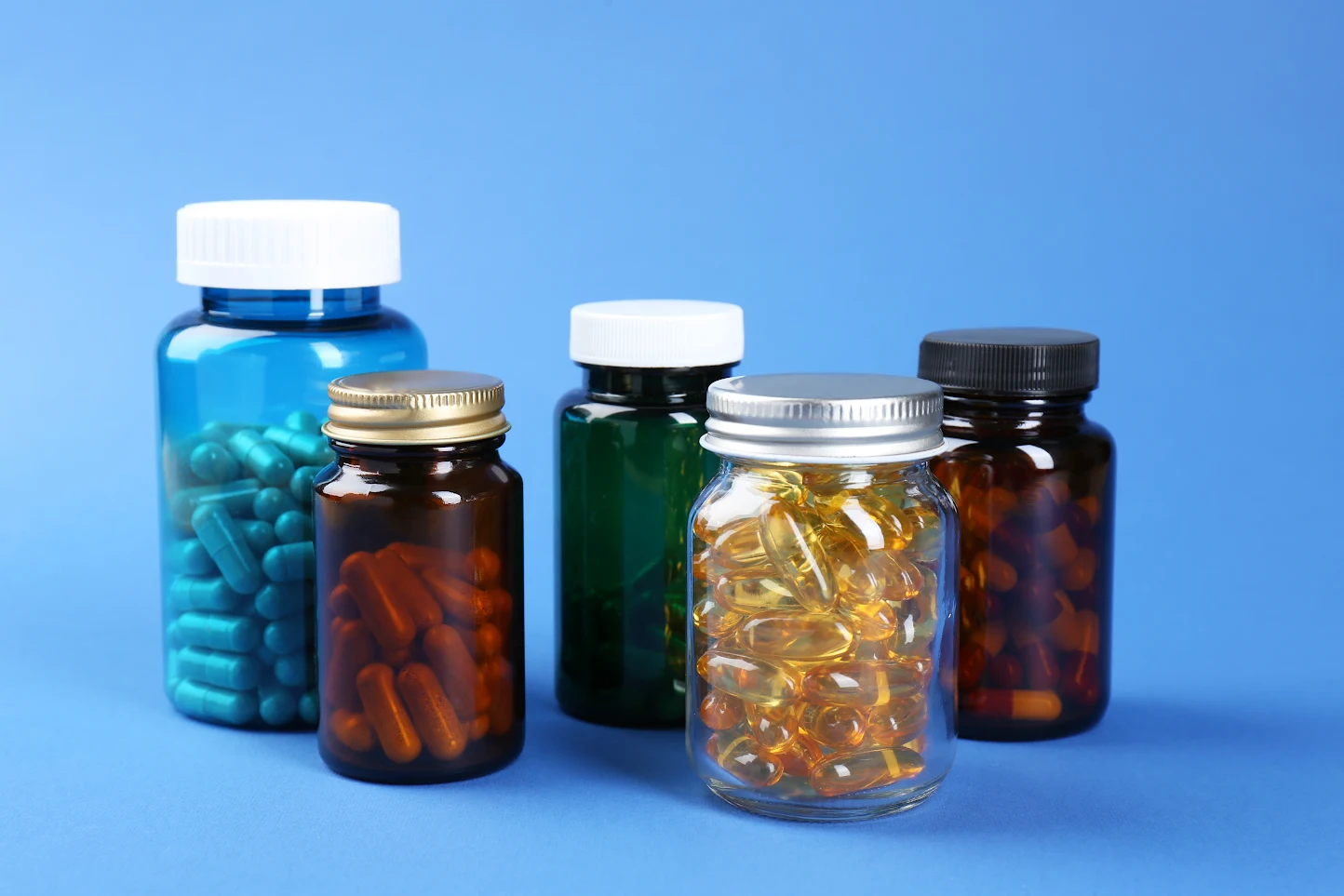 Assorted supplement capsules and bottles, illustrating how to choose a gentle iron form in Singapore
