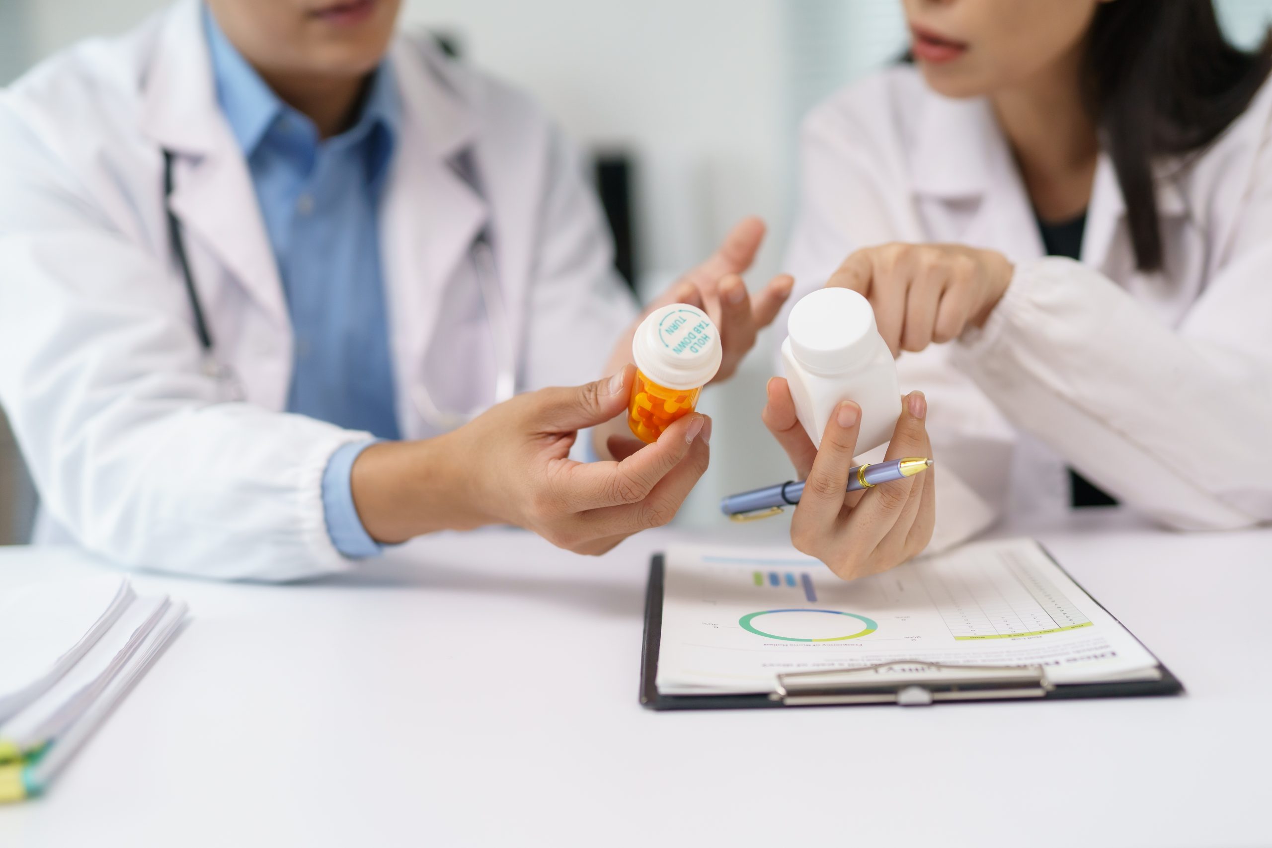 Two healthcare professionals comparing supplement bottles and reviewing dosage information, illustrating label terms to check on an omega 3 supplement